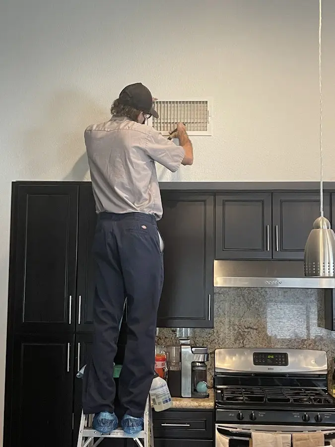 Technician inspecting an air vent during HVAC service in Homestead Meadows North